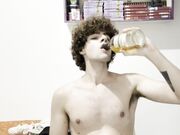Bellissimo ragazzo giovane beve rum nudo