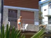 Milf in bikini si spalma la crema in terrazza