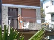 Milf in bikini si spalma la crema in terrazza