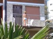 Milf in bikini si spalma la crema in terrazza