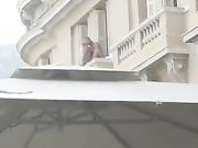 Aperitivo in piazza con coppia che scopa sul balcone