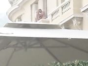 Aperitivo in piazza con coppia che scopa sul balcone